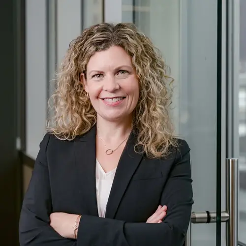 a woman with curly blonde hair wearing a black suit